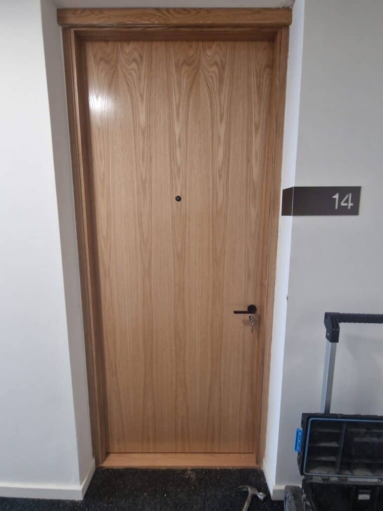 Wooden fire door with handle and key during installation in UK building