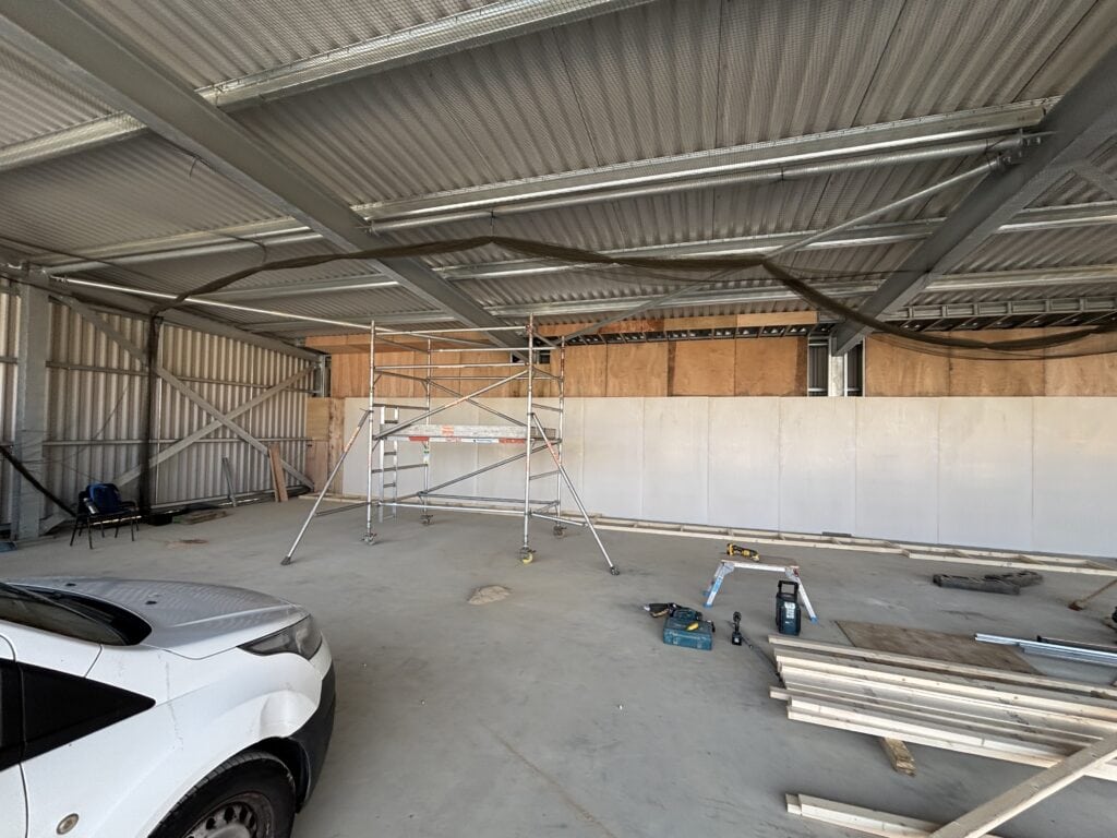 Scaffolding and tools during passive fire protection wall installation in UK hanger
